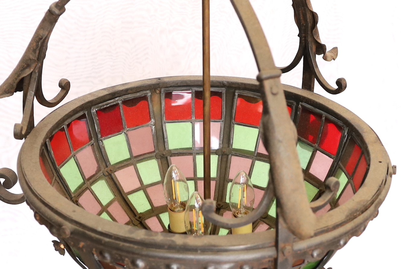 An English Arts & Crafts wrought iron and stained glass basket shaped light fitting, height 70cm to the top of the fitting with additional 10 link heavy wrought iron chain. width 52cm.